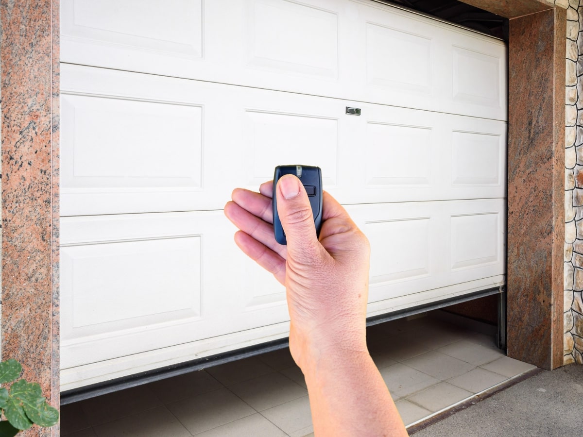 A hand holding a garage door remote control.