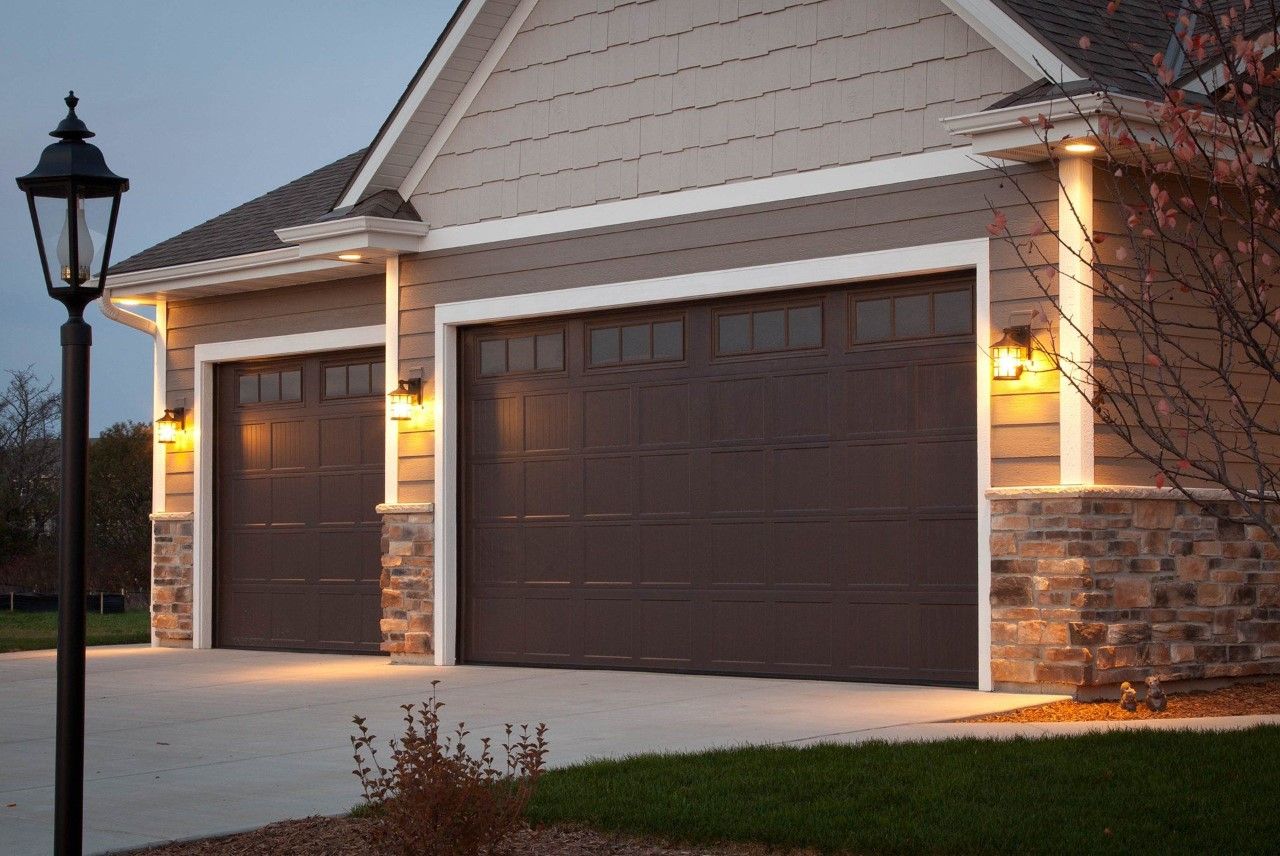 Two walnut-colored garage doors on a modern home.