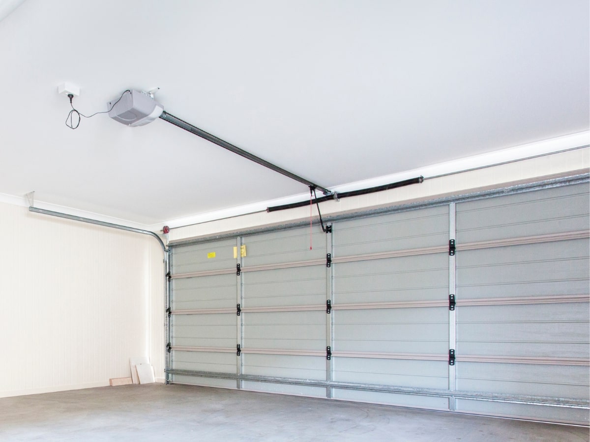 An inside view of a garage door, featuring the torsion springs and a ceiling-mounted opener.