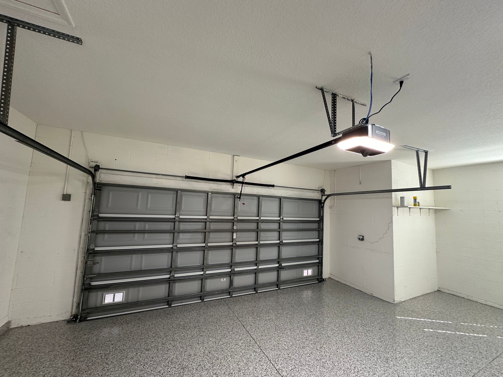 Overhead garage door opener and bright shop lights installed on a white garage ceiling.