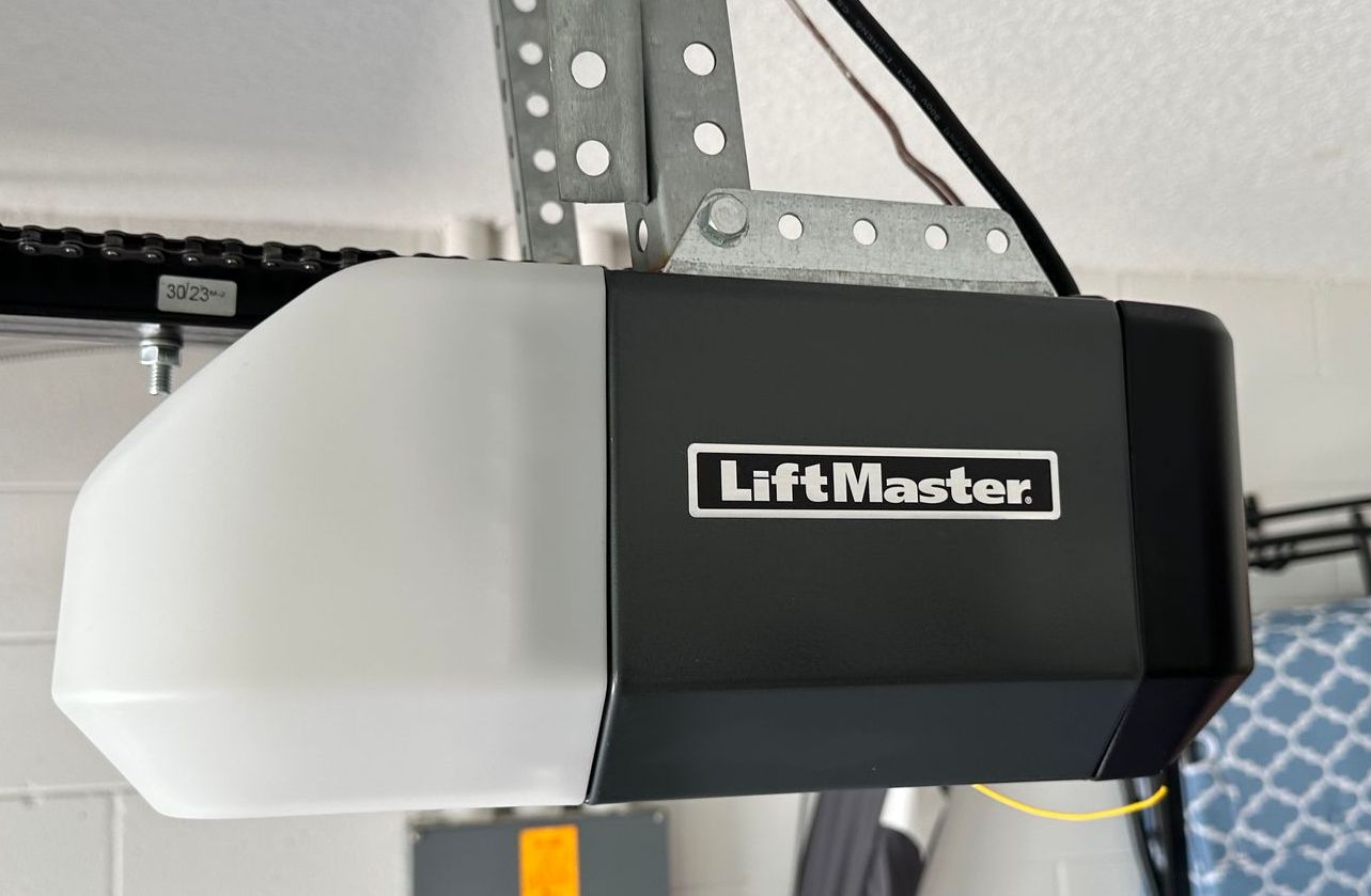 A technician in red overalls and a cap inspecting a garage door.